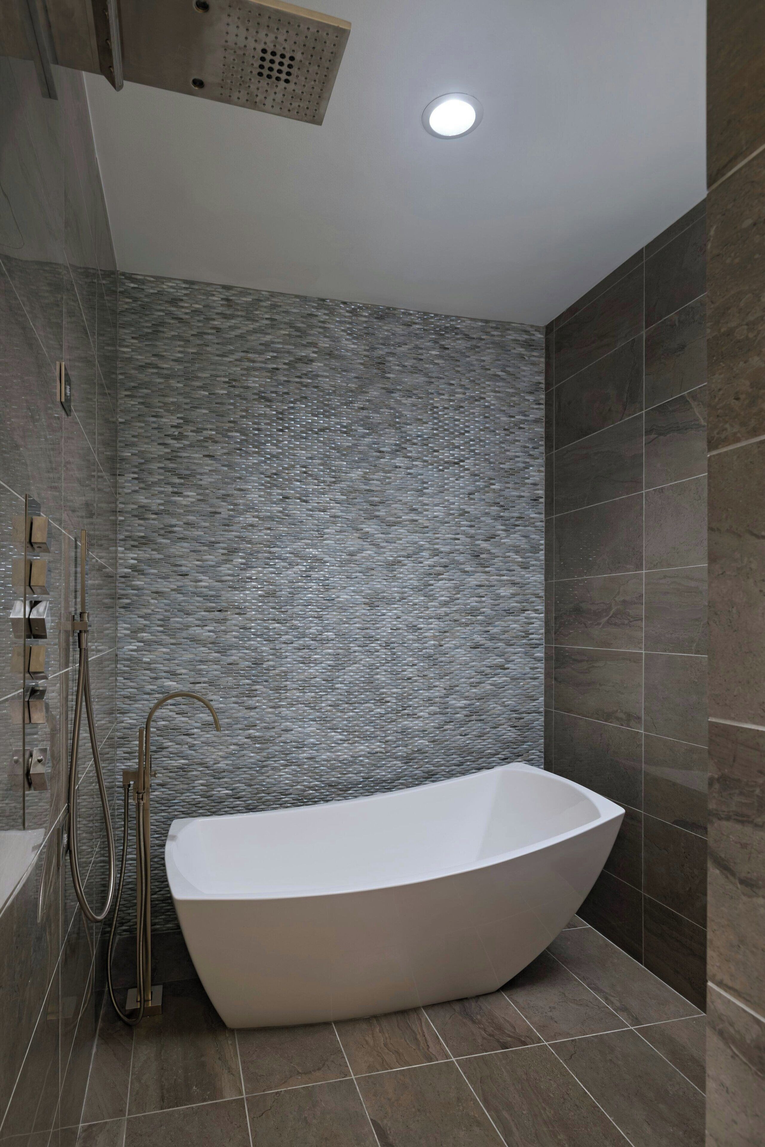 Une salle de bain moderne avec une baignoire sur pieds, une pomme de douche et un panneau de commande fixé au mur.