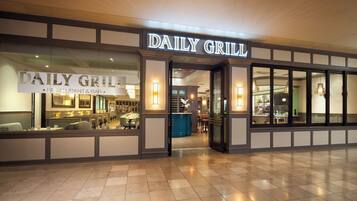 The exterior of a restaurant named "Daily Grill" with a modern design, featuring a prominent sign and a well-lit entrance.