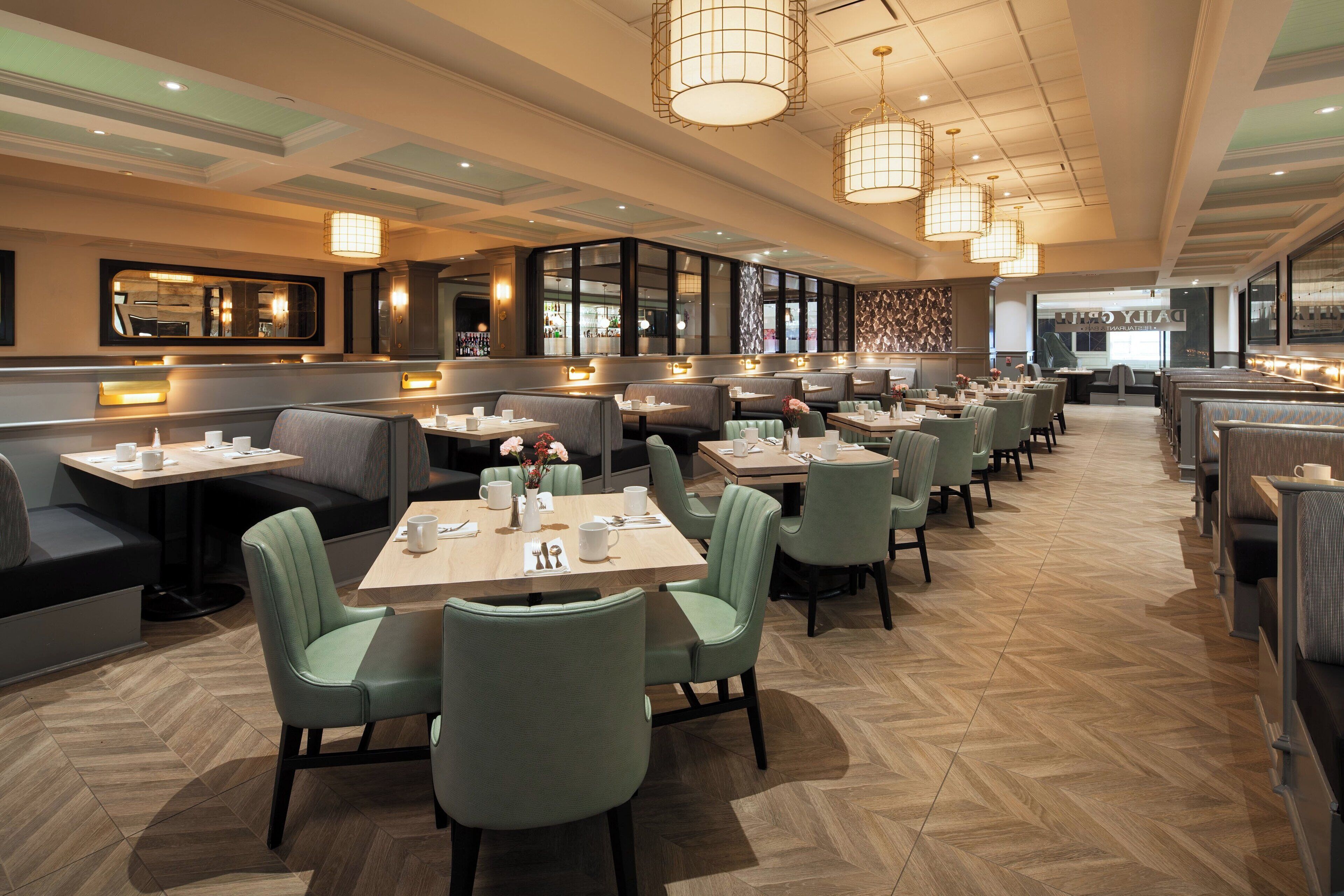En modern restaurang med flera olika sittområden, inklusive avskilda bås och bord, samt ett välpolerat trägolv.