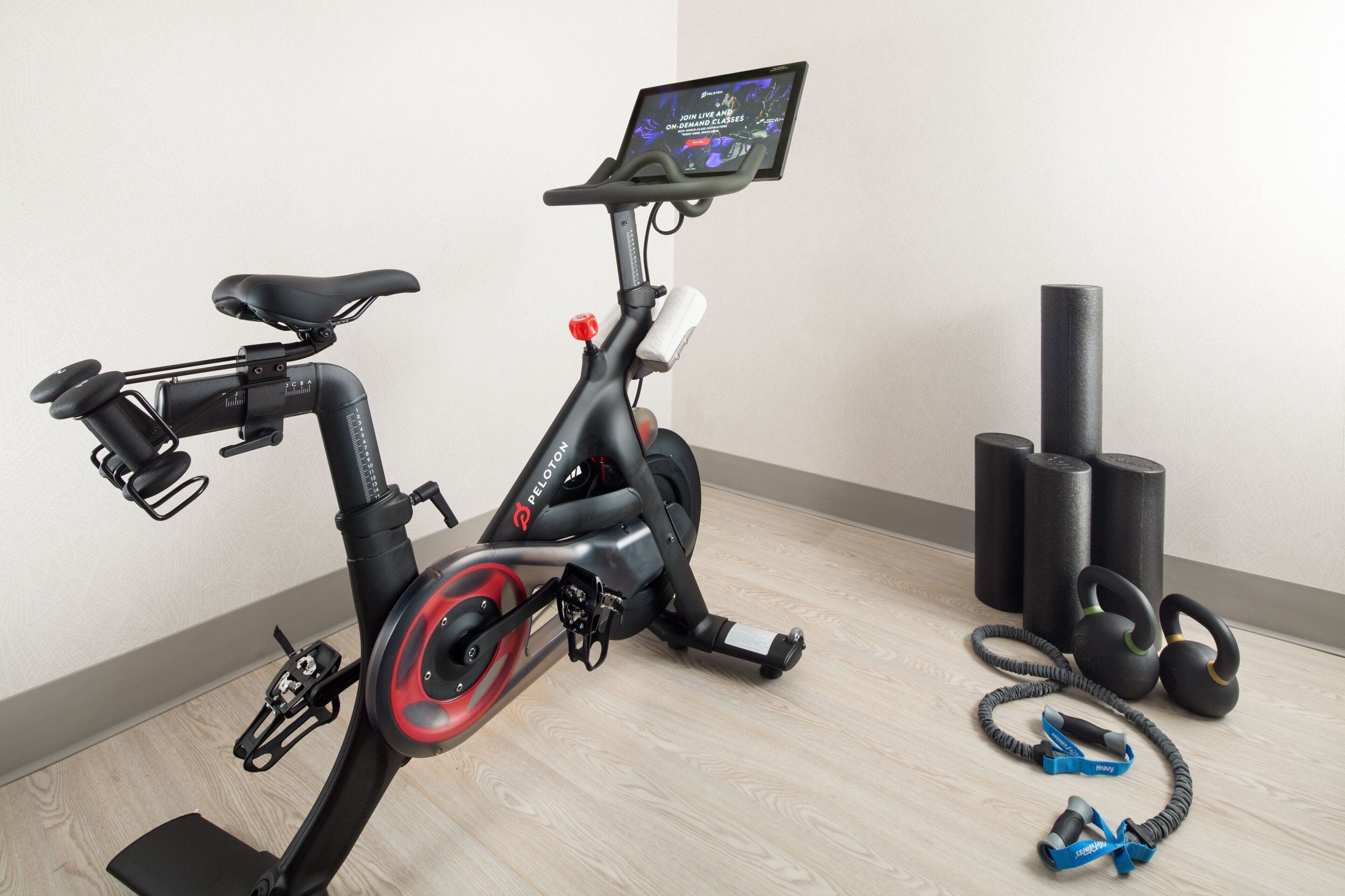 Una bicicleta estática con pantalla digital, asiento rojo y negro, y manillar.