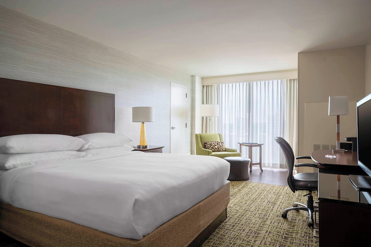 Een hotelkamer met een groot bed, een bureau met een computer, een stoel en een televisie.