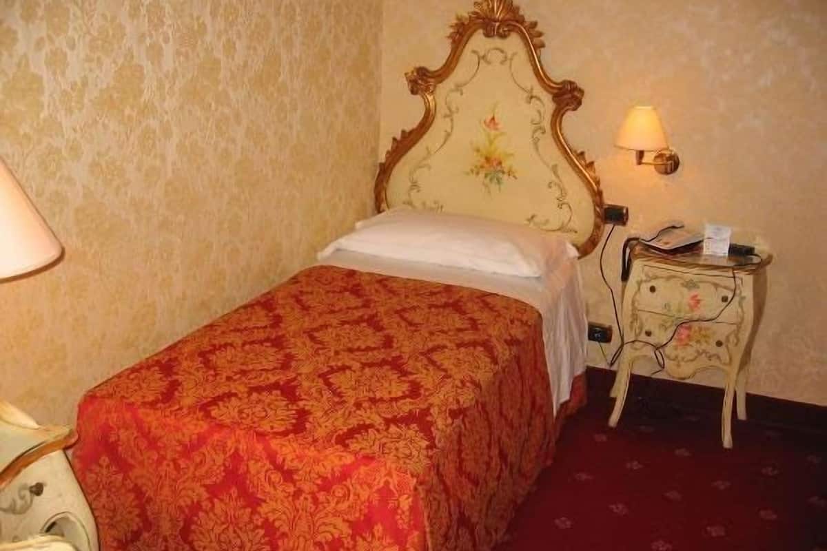 Una habitación de hotel con una cama, una mesita de noche y una lámpara.