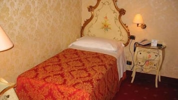 Una habitación de hotel con una cama, una mesita de noche y una lámpara.