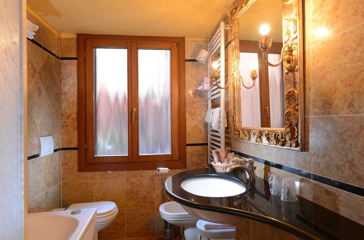 Ein Badezimmer mit Badewanne, Toilette, Waschbecken und einem großen Spiegel mit Zierrahmen.