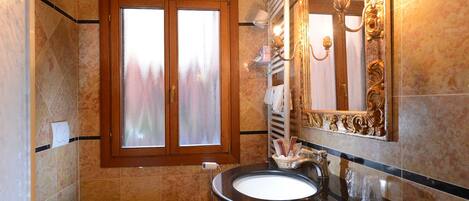 Ein Badezimmer mit Badewanne, Toilette, Waschbecken und einem großen Spiegel mit Zierrahmen.