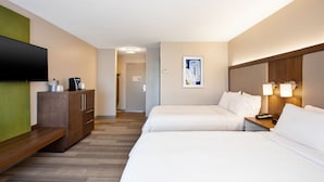 Une chambre d’hôtel avec deux lits, un téléviseur à écran plat, une machine à café et un tableau au mur.
