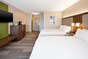 Quarto de hotel com duas camas, televisão de tela plana, cafeteira e um quadro na parede.