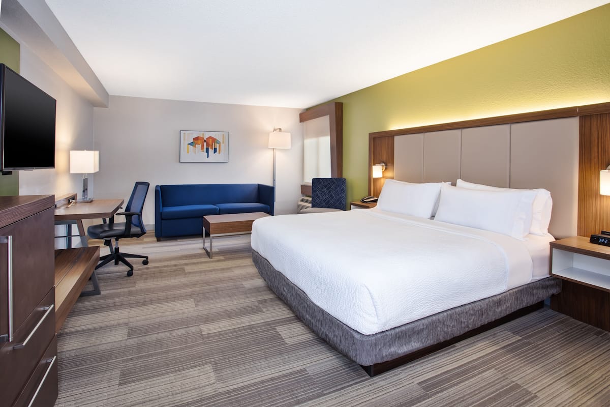 Une chambre d’hôtel avec un grand lit, un bureau avec une chaise, un canapé et une télévision.