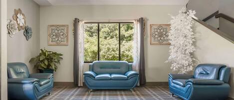 A living room with a blue sofa set, a potted plant, and decorative wall art.