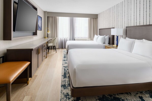 A hotel room with two beds, a desk, a chair, a TV, and a large window with curtains. - DoubleTree by Hilton Charlotte City Center (Charlotte)