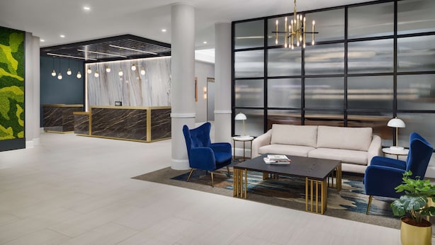 A modern lobby with a reception desk, seating area, and large windows.