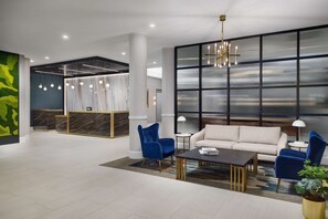 A modern lobby with a reception desk, seating area, and large windows. - DoubleTree by Hilton Charlotte City Center (Charlotte)