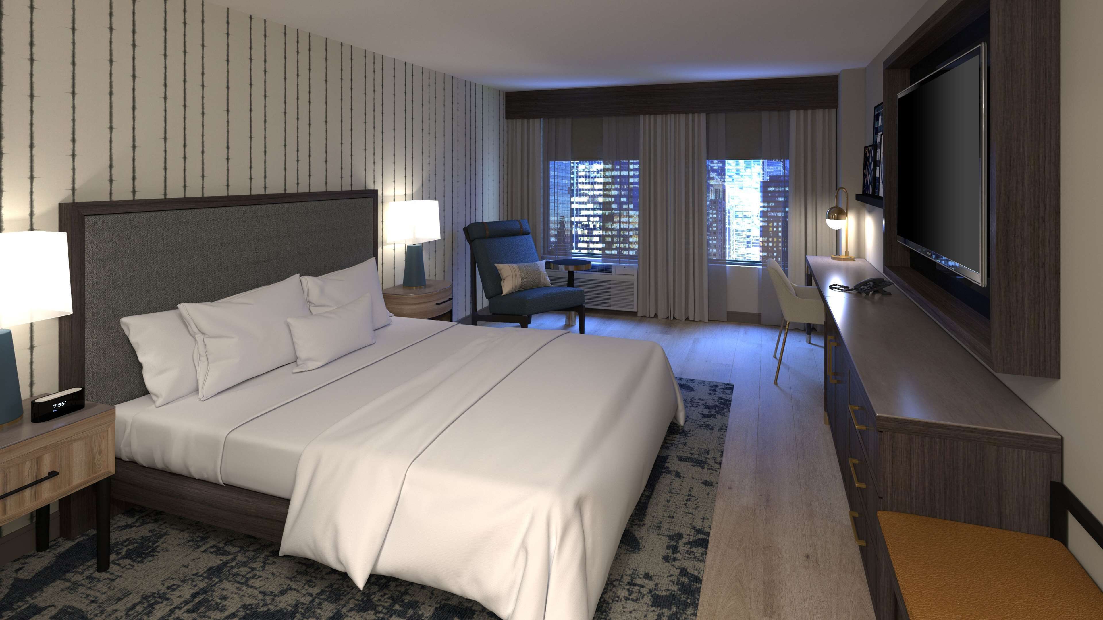 Quarto de hotel com uma cama grande, uma escrivaninha com televisão de tela plana, uma cadeira e janela com vista para a cidade.