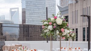 An outdoor event space with round tables, white chairs, and floral centerpieces.