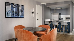A modern kitchen with a white countertop, stainless steel appliances, and a bar area with stools.