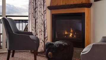 A cozy room with a fireplace, two armchairs, and a bear-shaped ottoman.