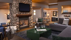 Una sala de estar moderna con chimenea de piedra, un televisor de pantalla plana montado en la pared, un sofá y una mesa de centro.
