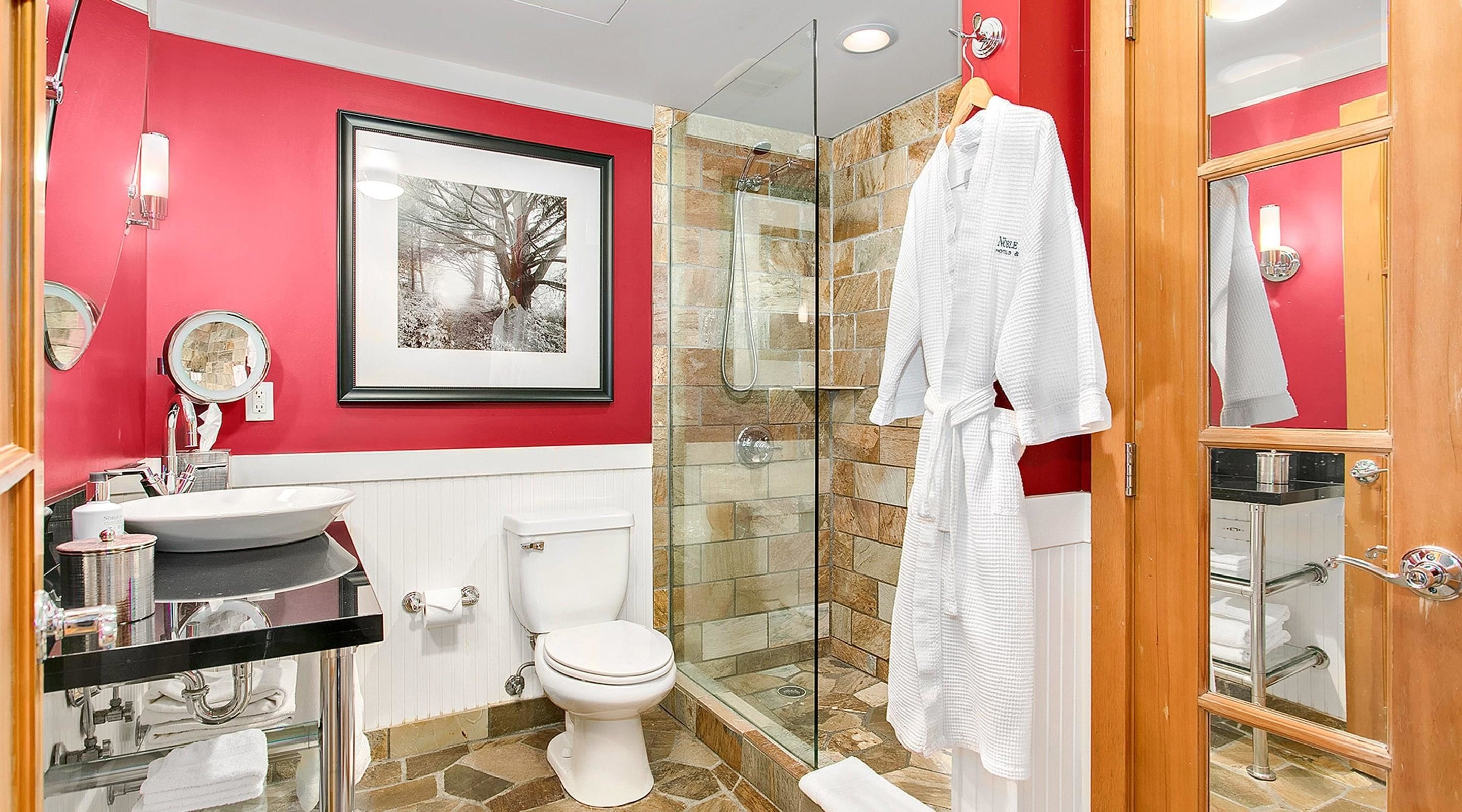 A bathroom with a glass shower, white toilet, and a sink with a mirror.