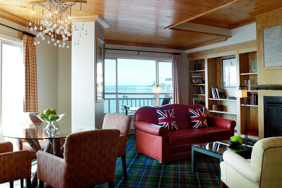 A living room with a red sofa, a glass coffee table, and a plaid carpet.