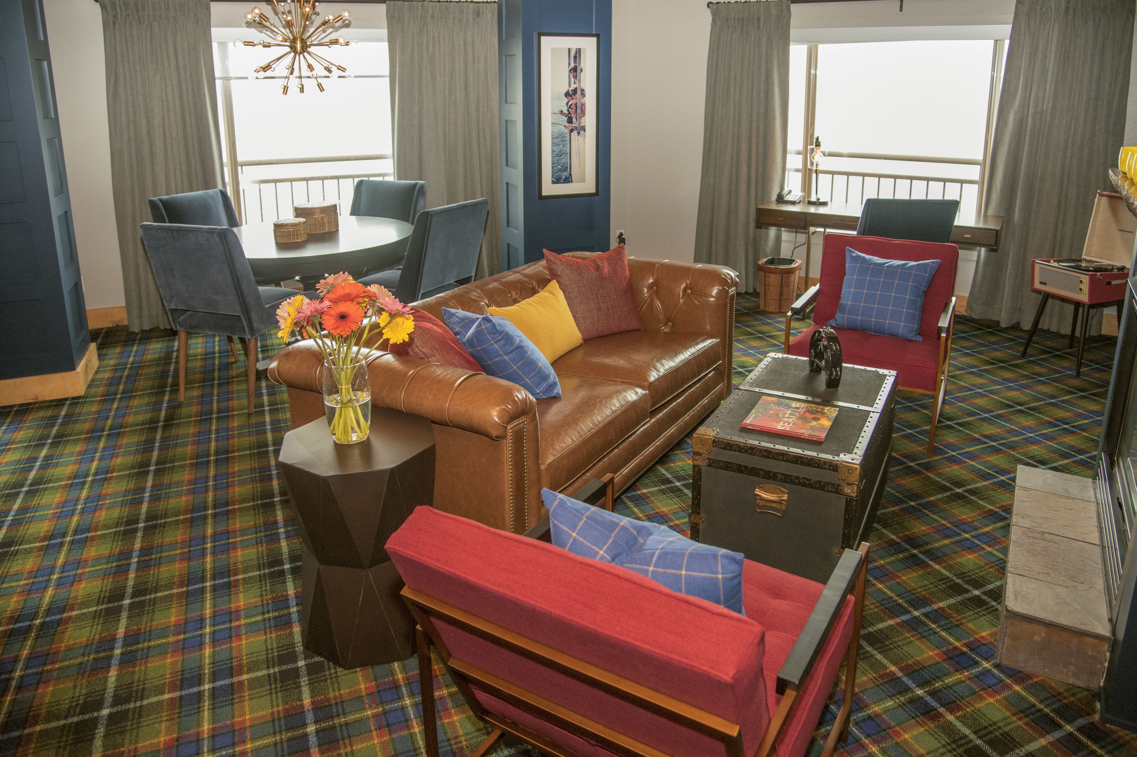 A living room with a plaid carpet, a brown leather sofa, a red armchair, and a coffee table.