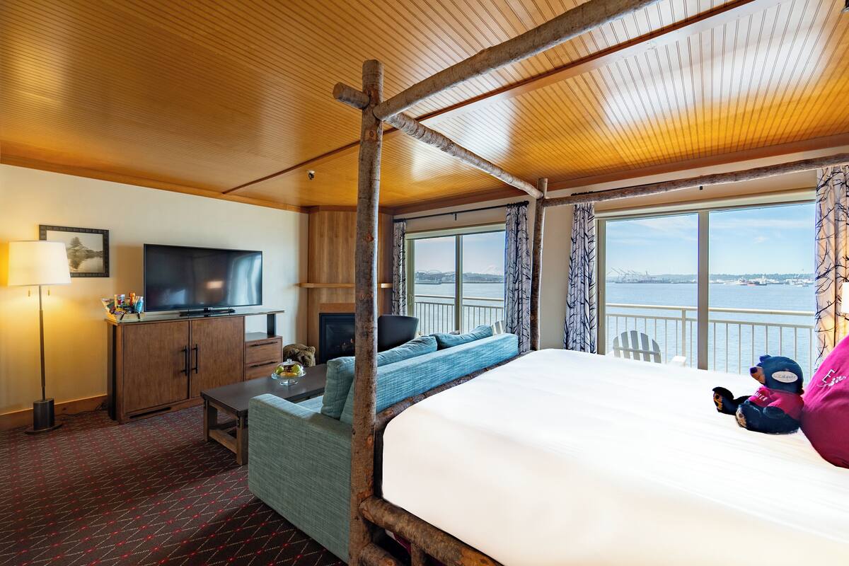 A room with a large bed, a television, a desk, and a view of the water.