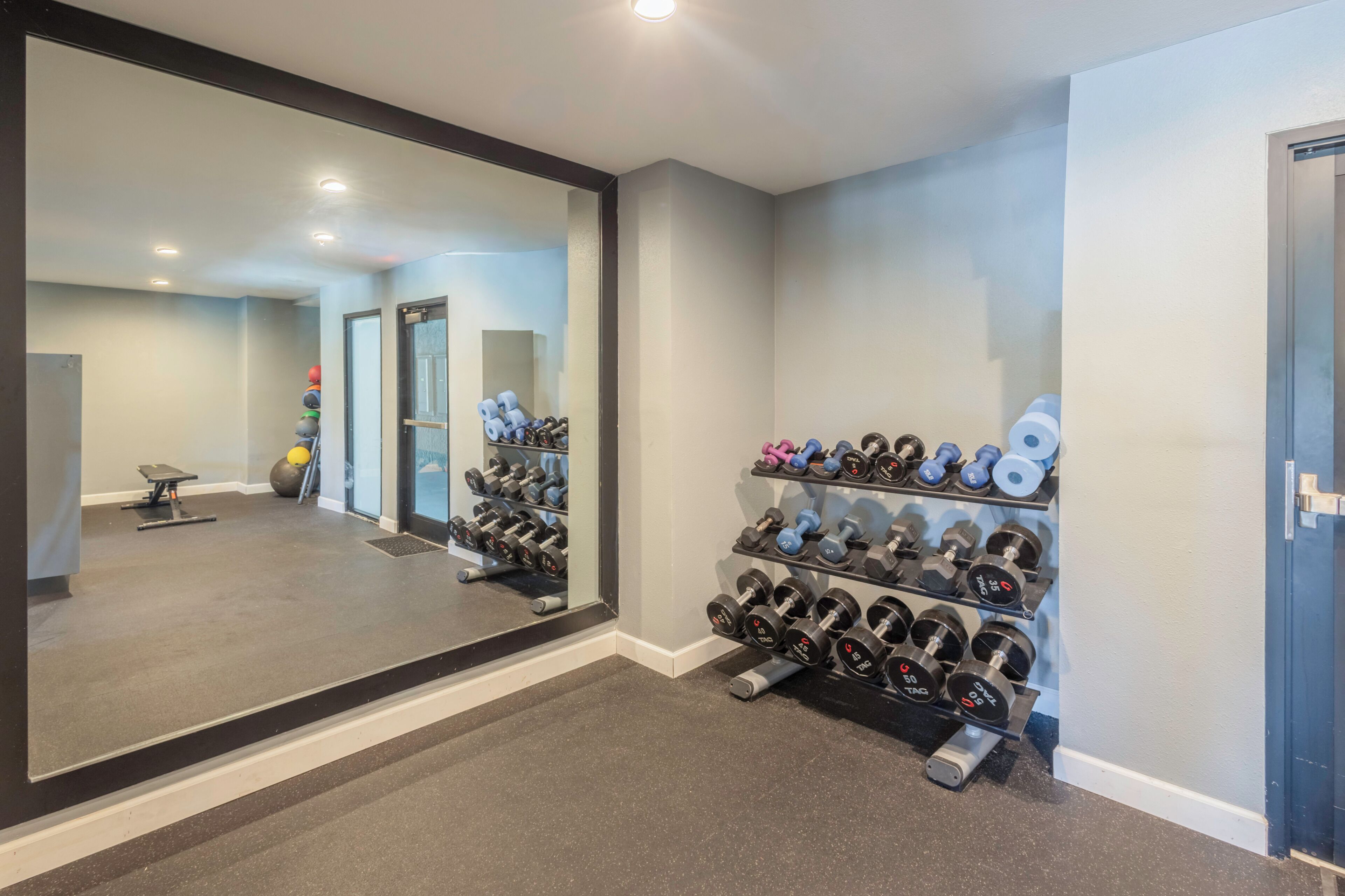 Ein Fitnessstudio mit großen Spiegeln, Gewichtsständern und Trainingsgeräten.