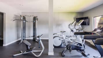 A home gym with a pull-up bar, a bench press, a stationary bike, and a treadmill.