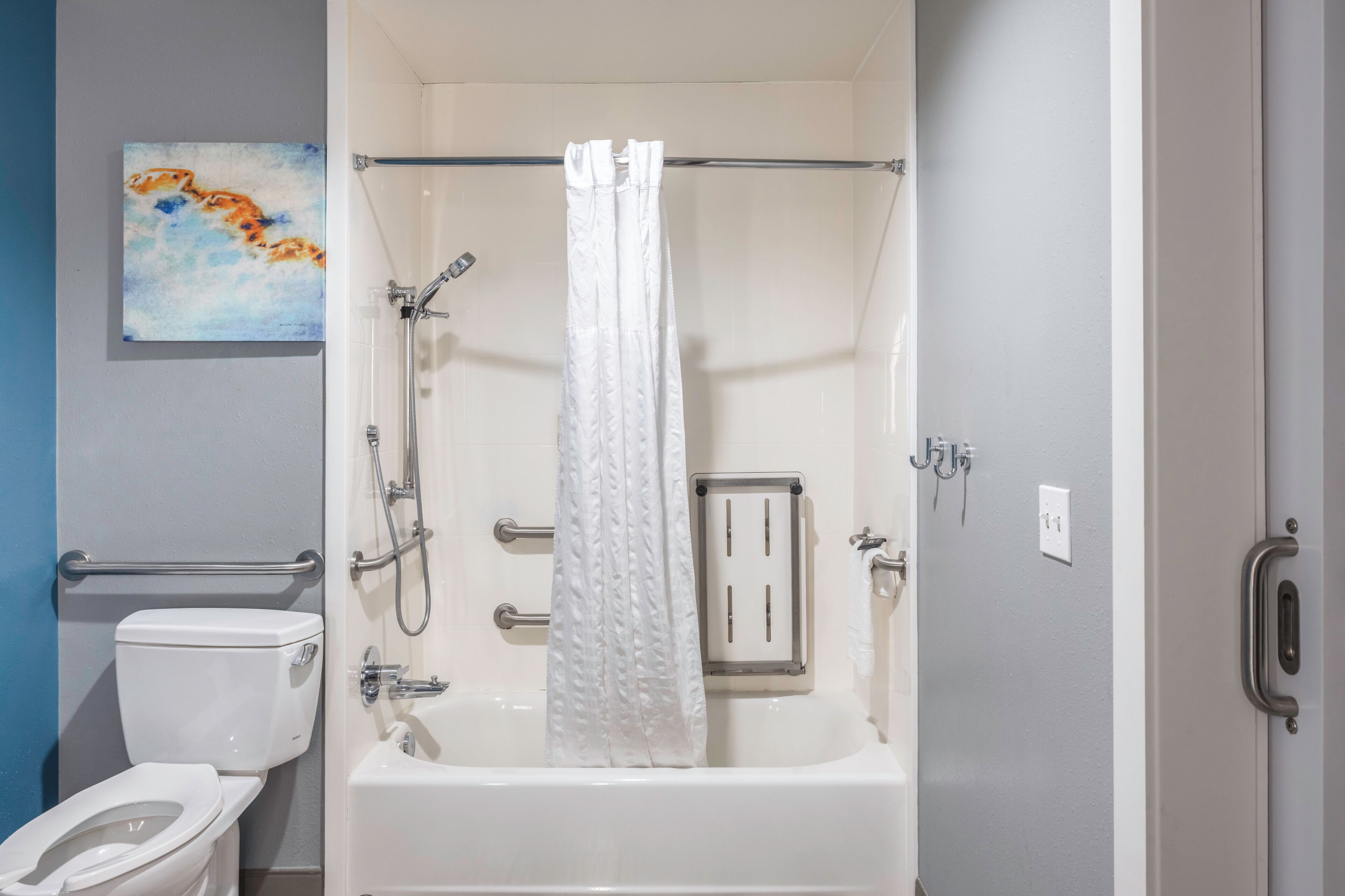 A bathroom with a toilet, a bathtub, a shower, and a towel rack.