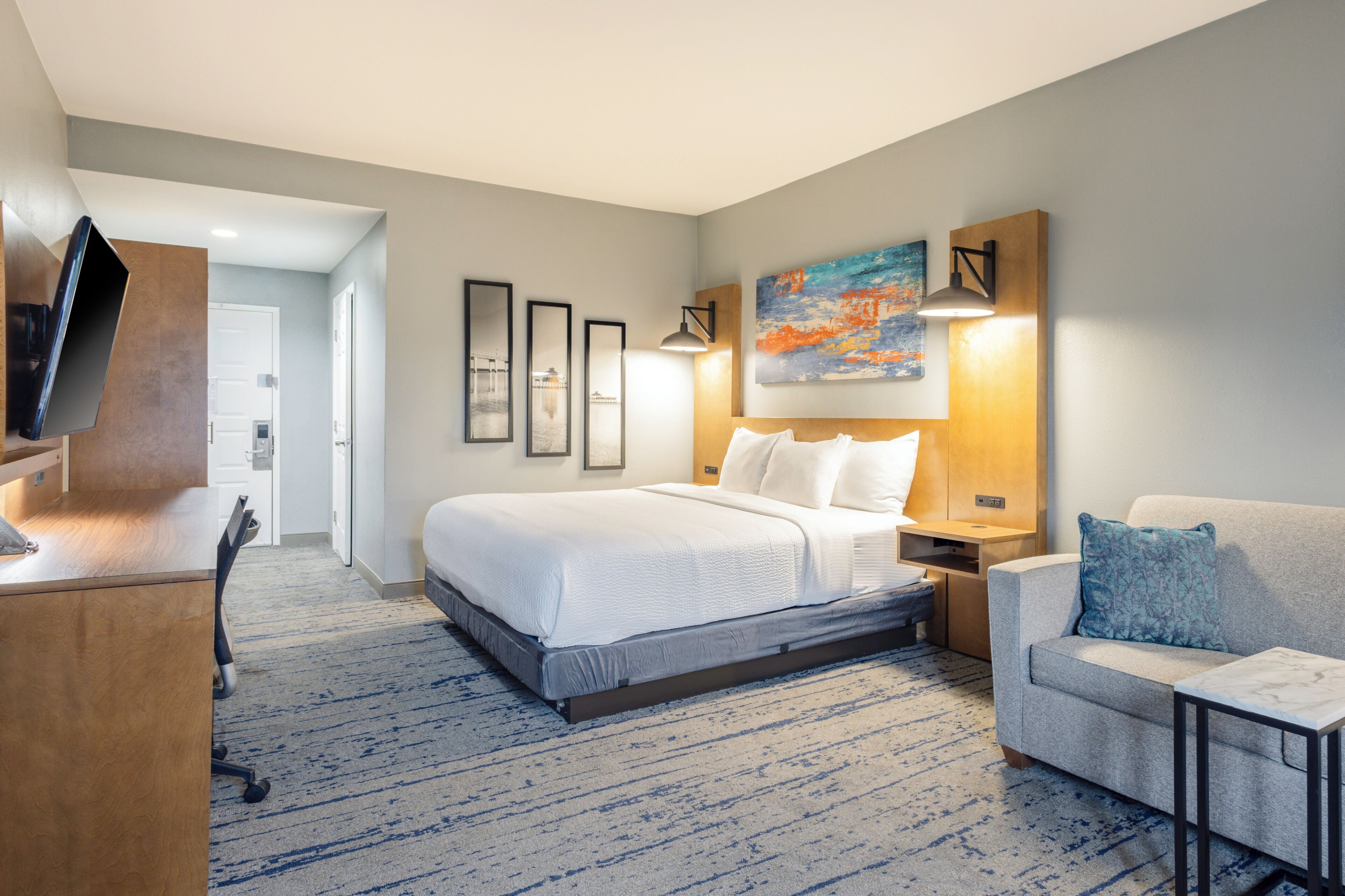 A hotel room with a bed, a desk, a chair, and a TV.