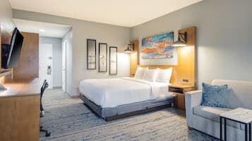 A hotel room with a bed, a desk, a chair, and a TV.