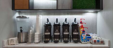 A coffee station with multiple coffee dispensers, a coffee maker, and a milk frother.