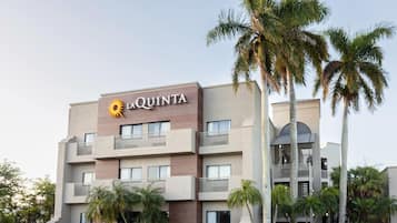 A multi-story hotel with balconies and palm trees.