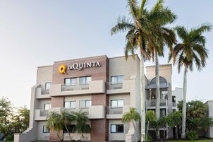Um hotel com várias andares, varandas e palmeiras.