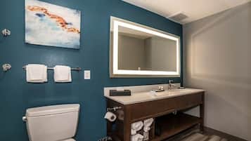 A bathroom with a toilet, a sink, a mirror, and a towel rack.