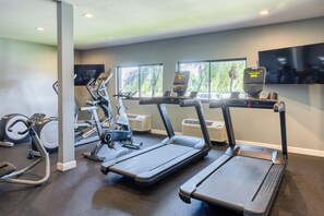 Une salle de sport équipée de tapis de course, d’appareils elliptiques et de vélos d’appartement.