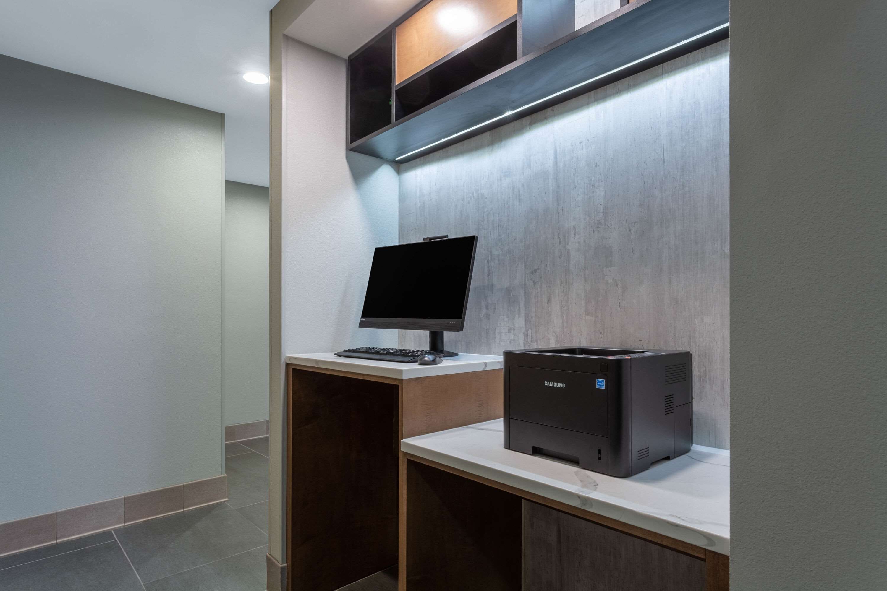 A modern office space with a desktop computer, a printer, and a shelf with storage boxes.