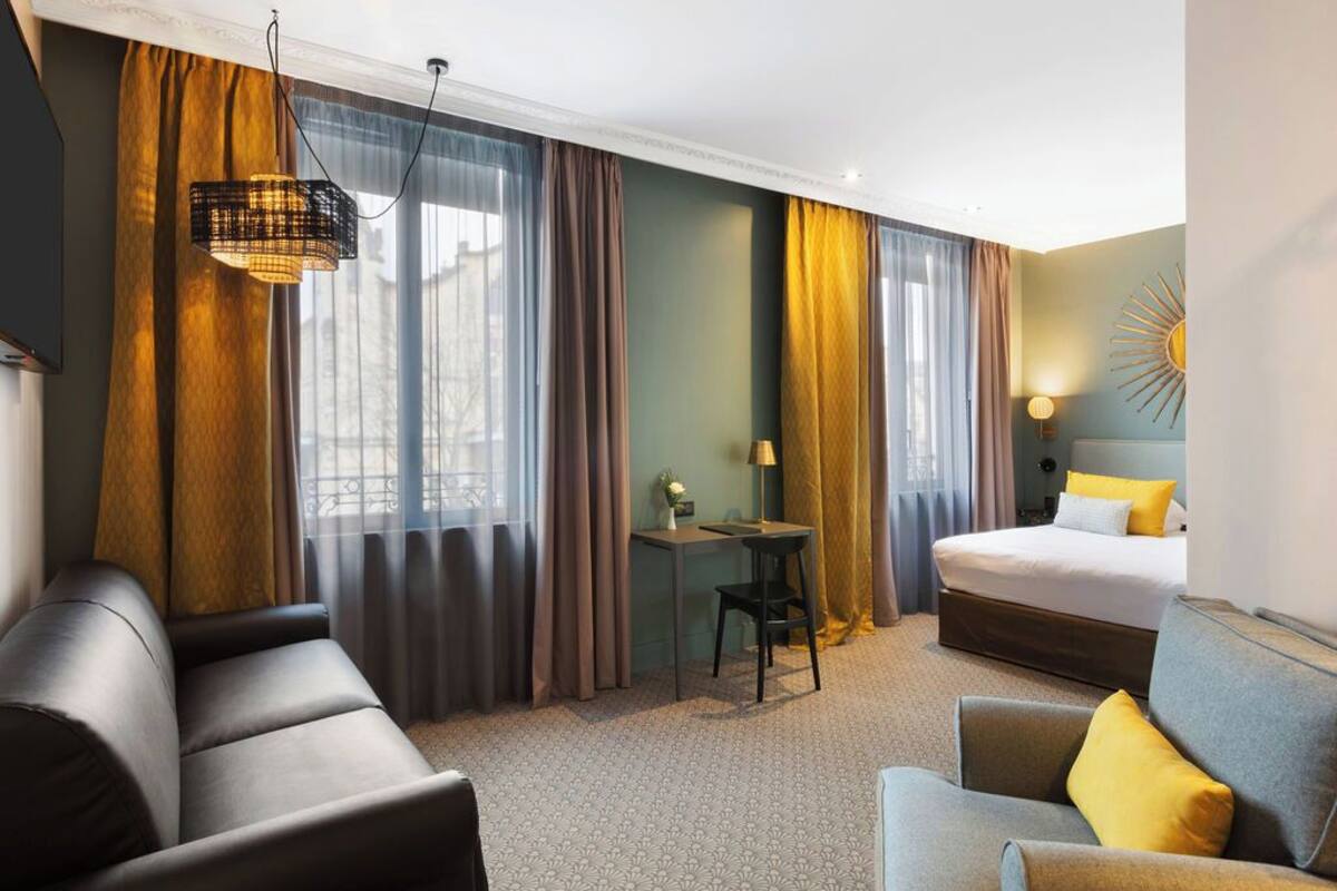 Een hotelkamer met een bed, twee banken, een tafeltje en een lamp.