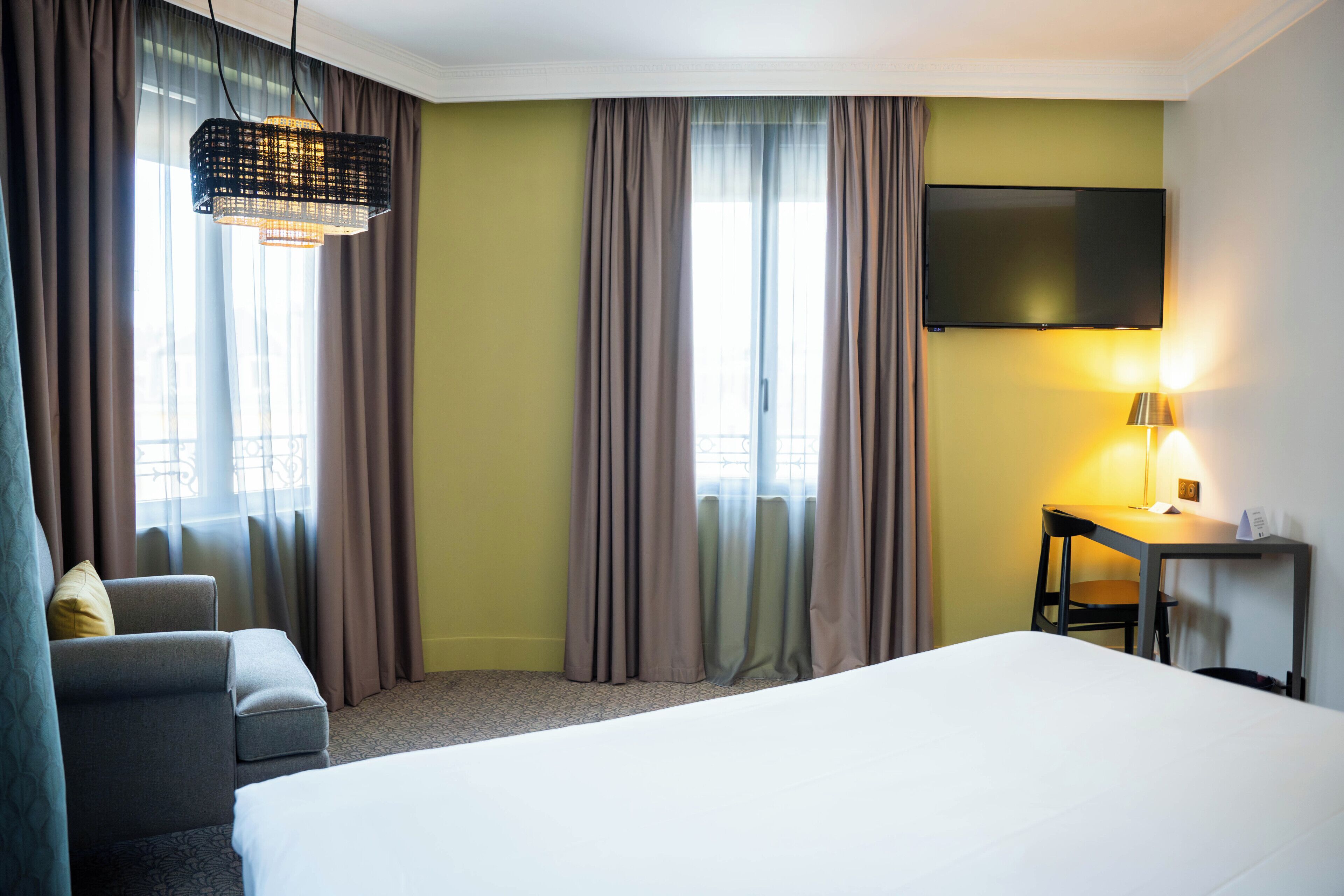 Une chambre d’hôtel équipée d’un lit, d’un bureau, d’une chaise et d’un téléviseur.