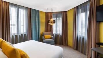 A hotel room with a large bed, a chair, a TV, and curtains.