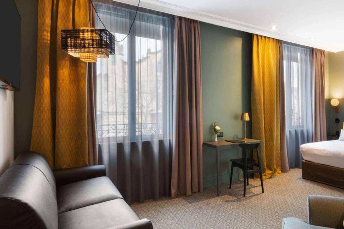 Een hotelkamer met een bed, een bureau, een stoel en een bank.