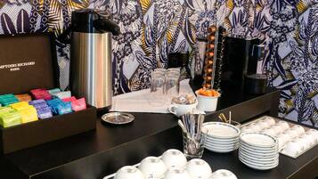 A buffet setup with a variety of food items, a thermos, and a decorative wall.