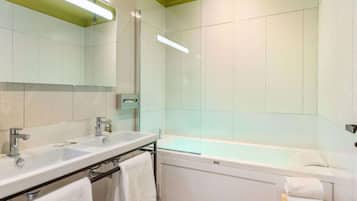 Un baño moderno con tocador de doble lavabo, ducha con mampara de vidrio y bañera independiente.