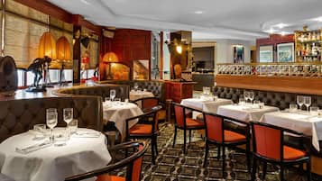 Um restaurante com mesas redondas, cabines acolchoadas e um espaço de bar.