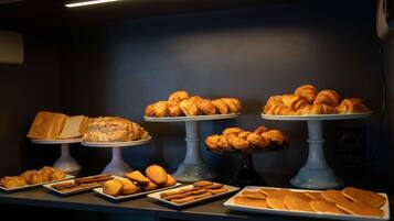 Un buffet proposant une variété de produits de boulangerie, notamment des pâtisseries, du pain et des biscuits.