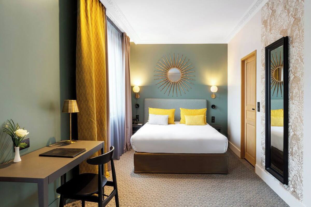 Een hotelkamer met een bed, een bureau, een stoel, een lamp en een spiegel.