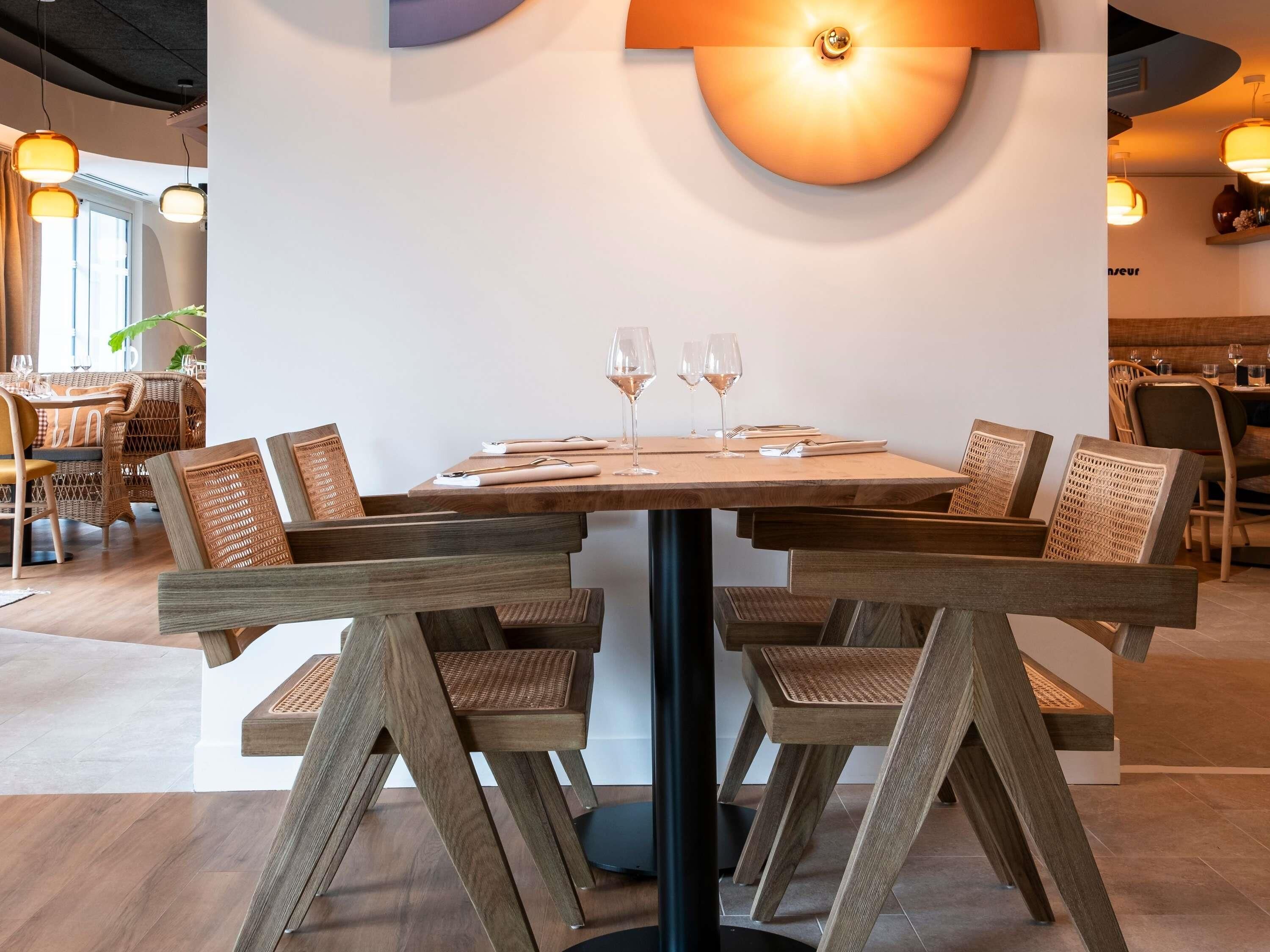 A dining area with a wooden table, wicker chairs, and a modern pendant light.