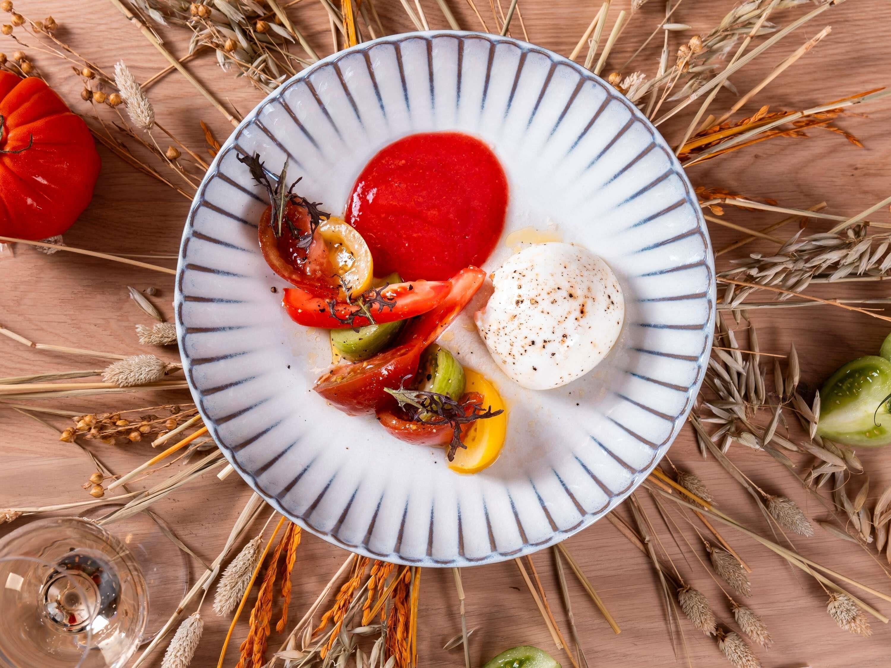 A plate with a white and blue rim, containing a red sauce, a poached egg, and grilled vegetables.