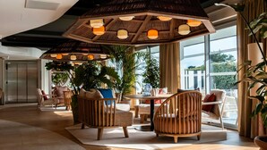 A modern interior with a large wooden ceiling structure, multiple seating areas, and large windows providing natural light. - Mercure Quiberon Hotel & Spa (Quiberon)