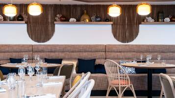 A modern restaurant interior with wooden panel walls, hanging pendant lights, and a mix of seating options including booths and chairs.