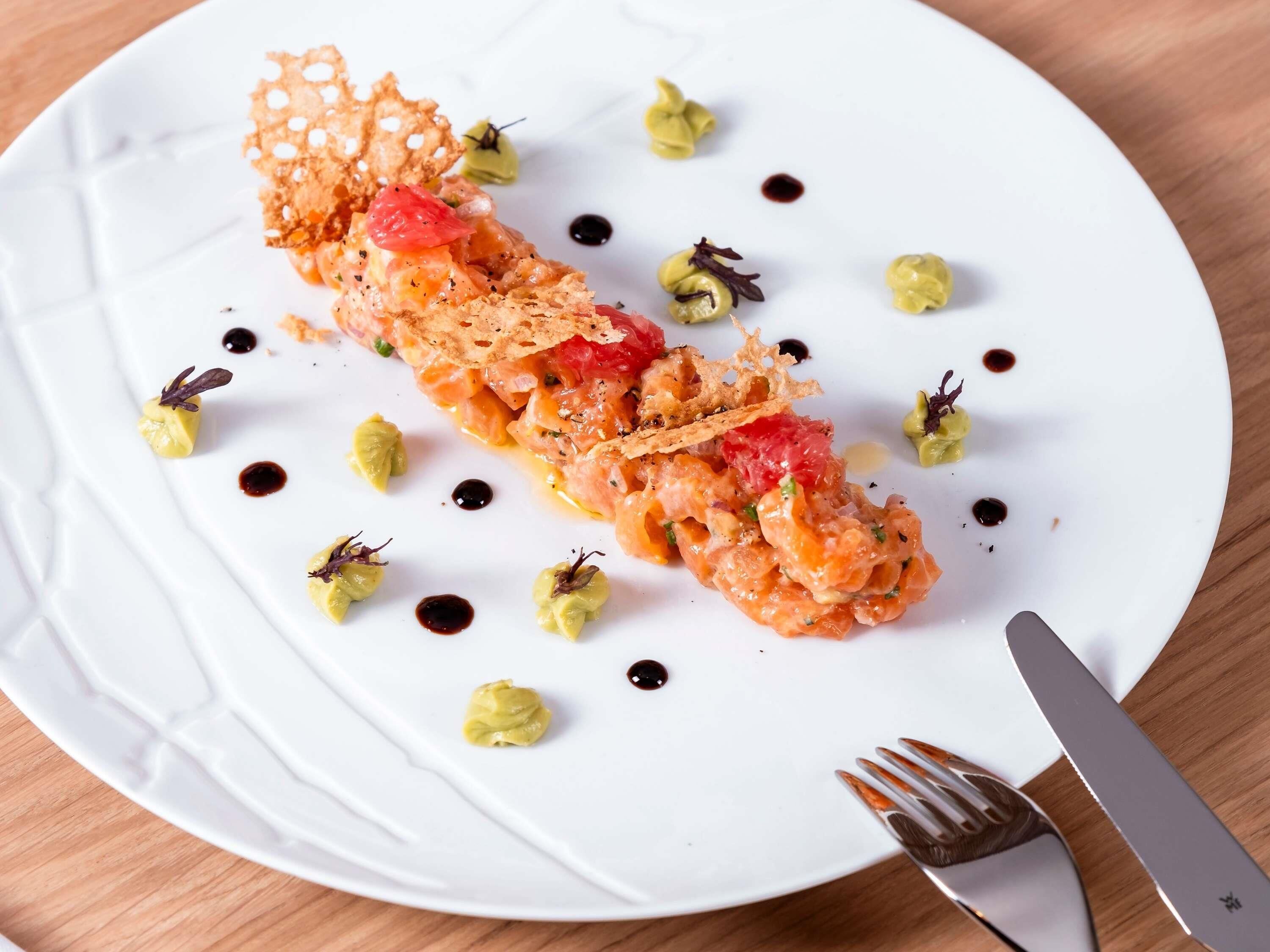 Un plato blanco con un aperitivo enrollado, adornos y salsas.